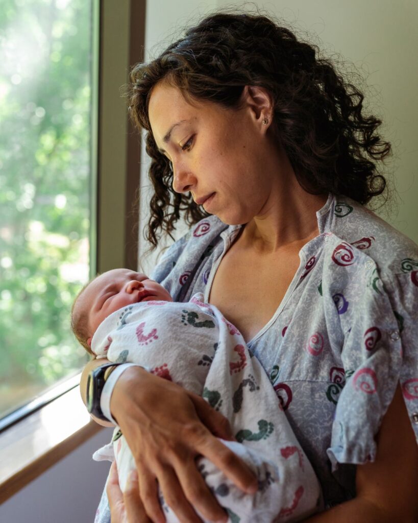 Young woman looks at her baby, before giving her up for adoption.