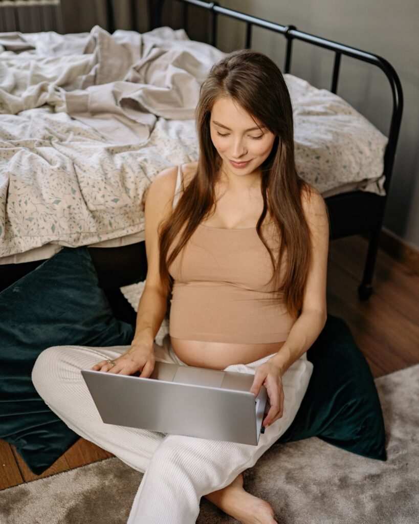 Pregnant college woman looking at her computer.
